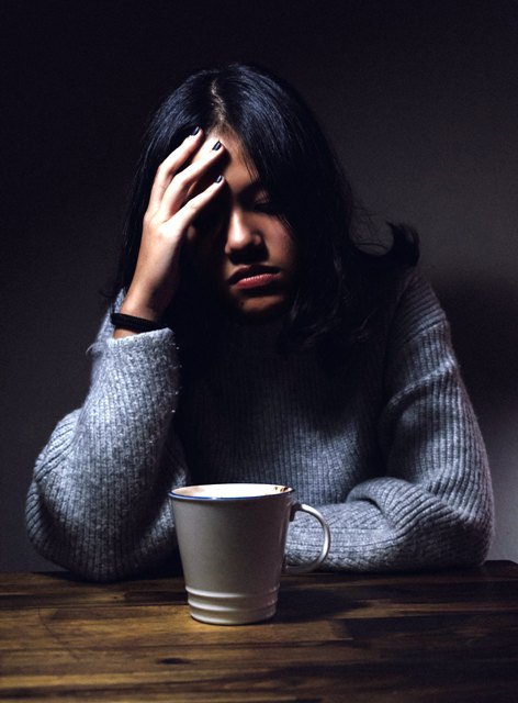 woman in darkened room with migraine